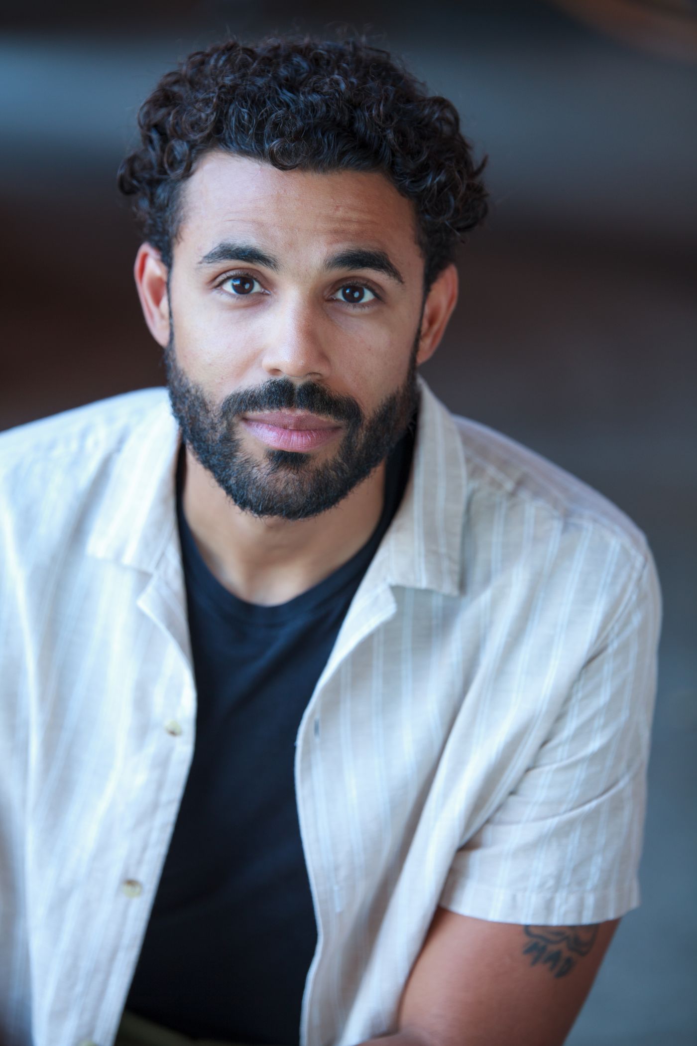 Headshot of Michael DiRoma in a striped linen shirt over a dark tee